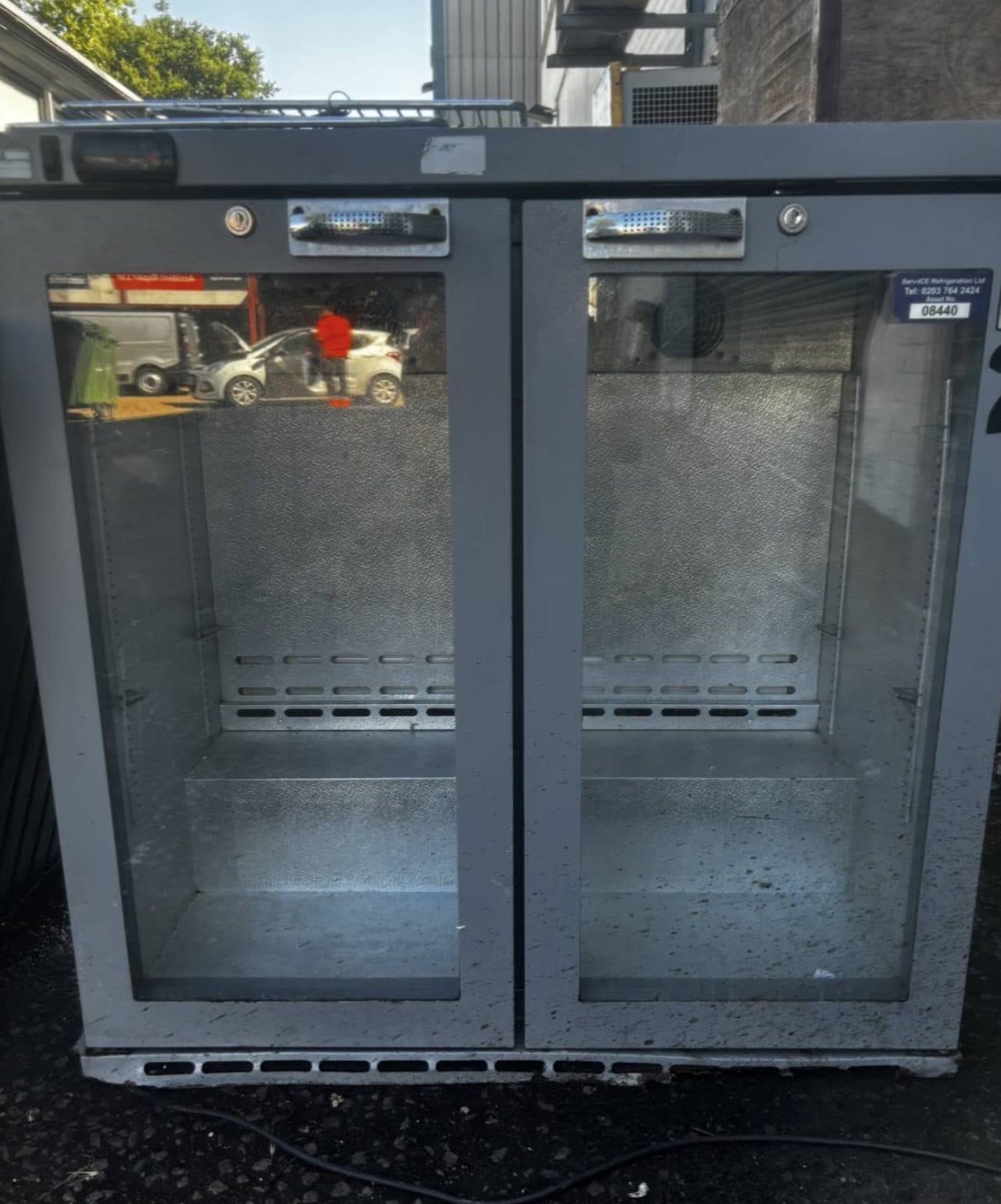Double-door commercial bottle fridge stripped from a unit and stood ready for collection