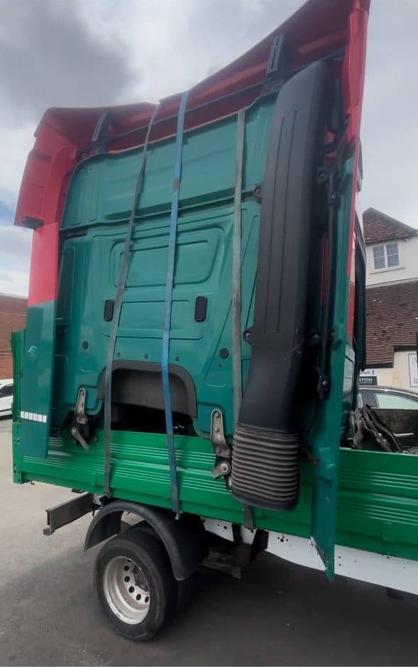 End-of-life HGV cab shell strapped onto the back of a tipper