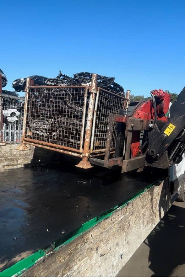 Lorry-mounted crane lifting a loaded stillage cage onto a flatbed