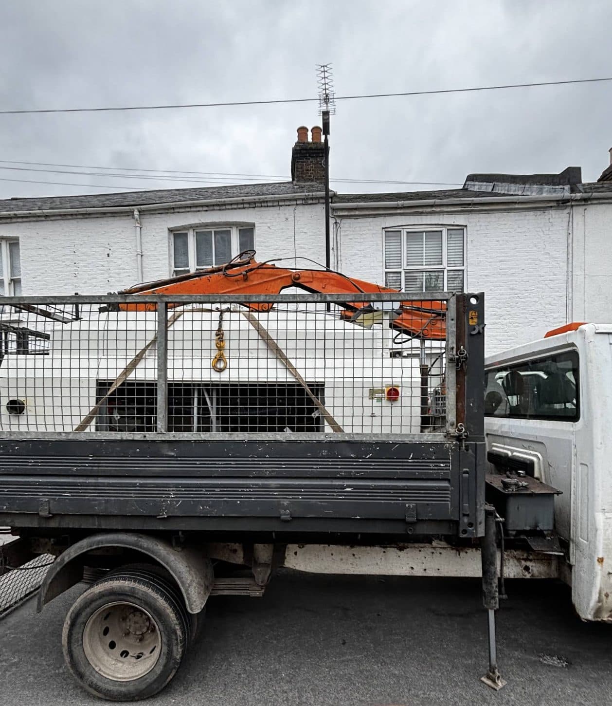 Caged tipper with its HIAB crane folded down, parked on a residential street