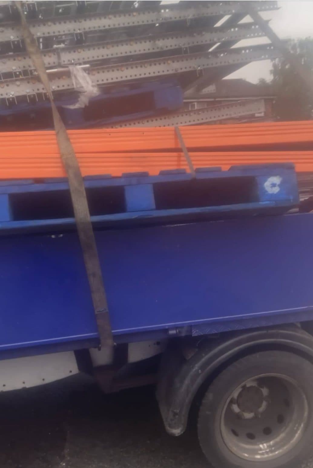 Dismantled pallet racking, uprights and beams strapped down on a flatbed