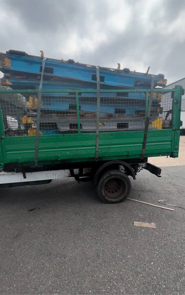 Painted steel beams stacked inside the cage of a tipper lorry