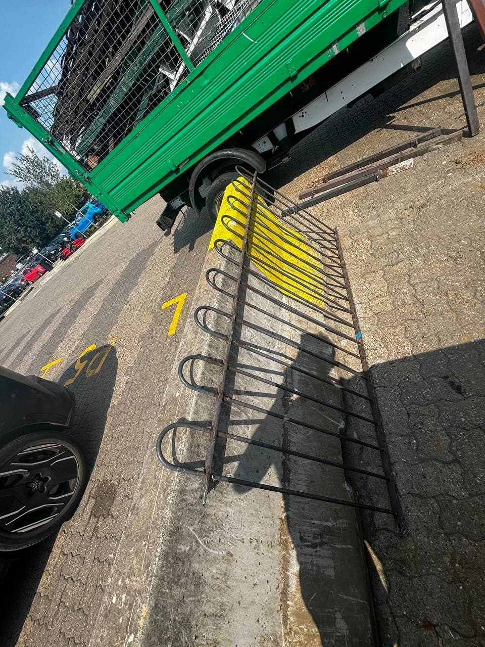 Steel railings unbolted and laid out on the kerb beside a caged tipper